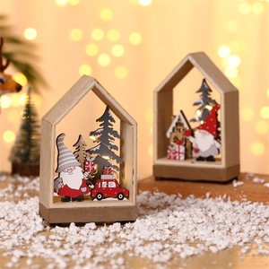 Close-up of wooden Christmas house cabin with warm LED light and Santa carvings