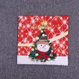 Close-up of red Christmas pillow case featuring a snowman, tree, and Welcome text