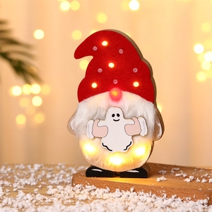 Close-up of wooden gnome decor with warm LED lights and ghost pattern on snowy wood base