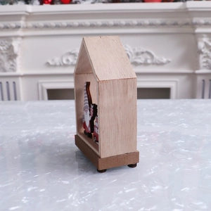 Detail of wooden Christmas house ornament with gnome and red gift bag on marble