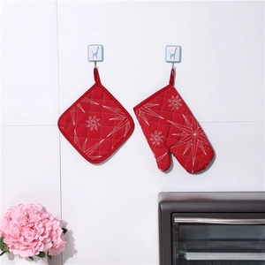 Detail of red quilted oven mitt and heat pad set with white geometric star pattern
