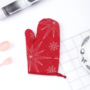 Detail of red oven mitt with white star pattern and hanging loop on kitchen background