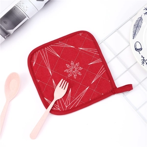 Red quilted heat-resistant pot holder with white geometric pattern and hanging loop