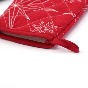 Detailed view of red quilted oven mitt with star patterns and a convenient hanging loop
