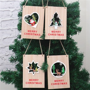Quatre ornements de Noël en bois avec Père Noël et rennes sur un sapin de Noël vert
