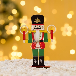 Colorful wooden nutcracker soldier figurine with glitter details on snowy background