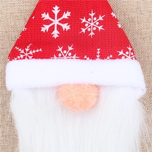 Close-up of a Christmas gnome bottle cover with red burlap hat and white faux fur beard