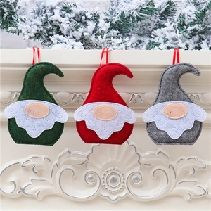 Close-up of handmade felt Christmas gnomes hanging with red ribbons on a mantel