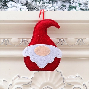 Detail of red and white felt Christmas gnome ornament hanging on an evergreen branch