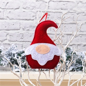Macro view of handmade red Christmas gnome ornament with white embroidered beard on a tree