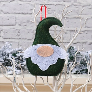 Close-up of a handmade dark green felt Christmas gnome ornament with a white beard