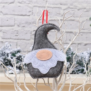 Close-up of handmade felt faceless gnome ornament with red ribbon on winter background