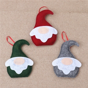 Close-up of three felt Christmas gnomes with pointed hats and ribbons on burlap fabric