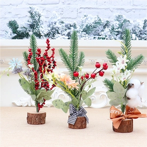 Close-up of three mini tabletop Christmas trees with red berries and wooden bases