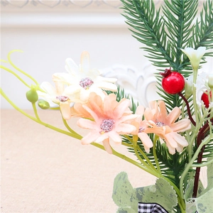 Detail of mini Christmas tree featuring pink daisies, red berries, and green pine needles