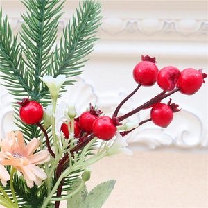 Close-up of mini Christmas tree with red berries, pine needles, and a daisy ornament