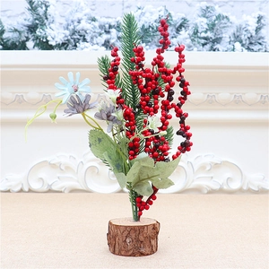Close-up of mini Christmas tree with red berries, blue daisies, and a natural wooden base