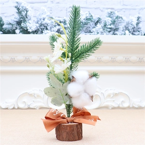 Close-up of mini Christmas tree with red berries, cotton flower, and a wooden base