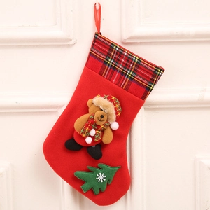 Detail of red plush Christmas stocking featuring a 3D teddy bear and green tree applique