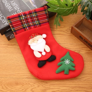 Close-up of a red plush Christmas stocking with a 3D Santa doll and tartan cuff detail