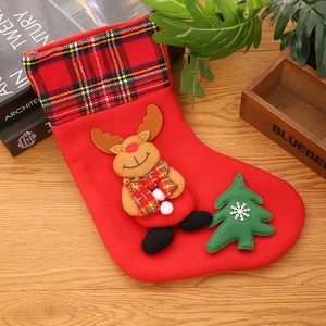 Detail of red Christmas stocking with plaid trim and a cute plush 3D reindeer mascot