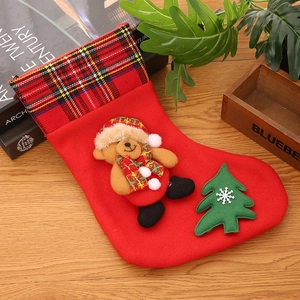 Detail of red Christmas stocking with plaid trim and cute 3D plush bear decoration