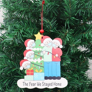 Christmas wooden ornament with masked family design hanging on a green festive tree