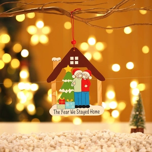 Adorno navideño de madera con diseño de casa y tema de pandemia colgado en ramas doradas