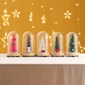 Close-up of five mini Christmas glass domes with glowing miniature trees and wooden base