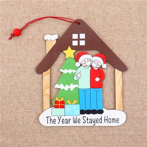 Detalle del adorno de madera con figuras enmascaradas y texto The Year We Stayed Home
