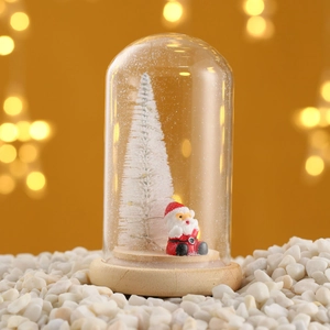 Detail of Christmas glass dome with a miniature white tree and red Santa Claus figure