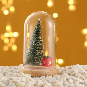 Miniature Christmas tree with red gift box in glass dome on rustic wooden base