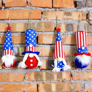 Set of 4 Independence Day plush gnomes with stars and stripes hanging on a brick wall