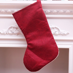 Close-up of a large dark red felt Christmas stocking hanging on a white vintage fireplace