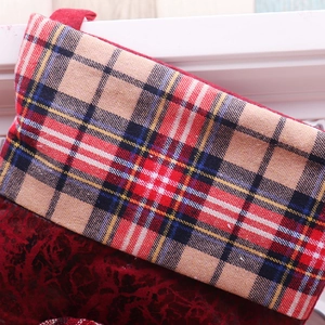 Detail of red embossed velvet Christmas stocking with a colorful tartan plaid cuff and loop