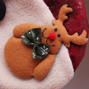 Macro detail of felt reindeer with red pom-pom nose on plush Christmas stocking