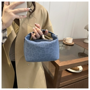 Blue leopard print suede handbag with gold accents shown in a lifestyle cafe setting