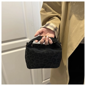 Detail der schwarzen Handtasche mit Leopardenmuster, goldene Ringe und matte Textur