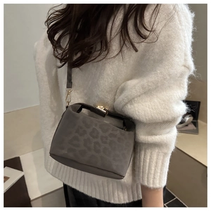 Grey leopard print small crossbody bag with gold buckle on a white sweater background