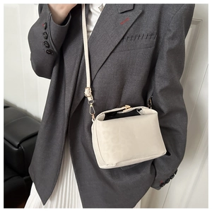 Détail d'un sac nuage blanc crème avec boucle dorée sur un blazer gris chic