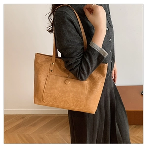 Detail of light brown crocodile pattern tote bag with large capacity and textured surface