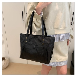 Detail of black crocodile texture tote bag with gold studs and front snap pocket