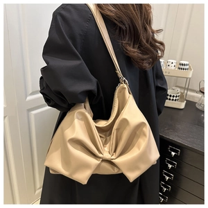 Close-up of beige shoulder bag featuring a large decorative bow and soft PU leather texture
