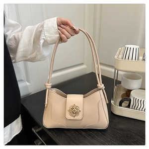 Detail of elegant beige shoulder bag featuring a vintage gold floral buckle and knot straps
