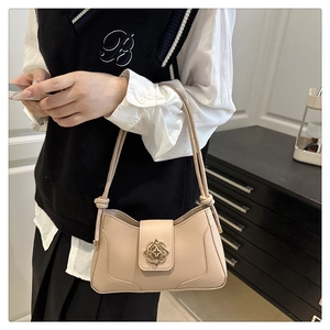 Detail of beige underarm baguette bag featuring golden hollowed buckle and shoulder strap knot