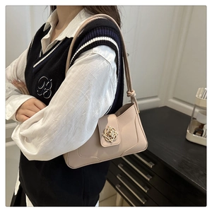 Beige faux leather shoulder bag featuring a decorative gold flower buckle closure