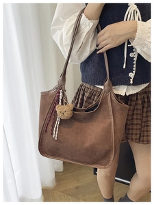 Detail of vintage brown suede hobo bag featuring a plush bear charm and woven rope accents