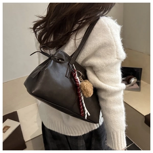Détail du cabas marron foncé avec cordon en cuir et breloque pompon en peluche