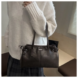 Detail of dark brown tote bag with metallic fashion plaque and side drawstring accents