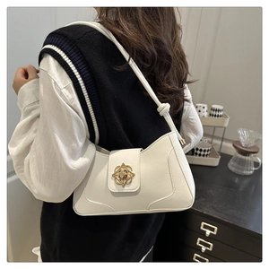 Close-up of white leather shoulder bag with golden floral metal buckle and knot strap detail